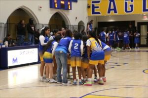 The Lady Eagles basketball team huddled during a game at East Grand Preparatory.